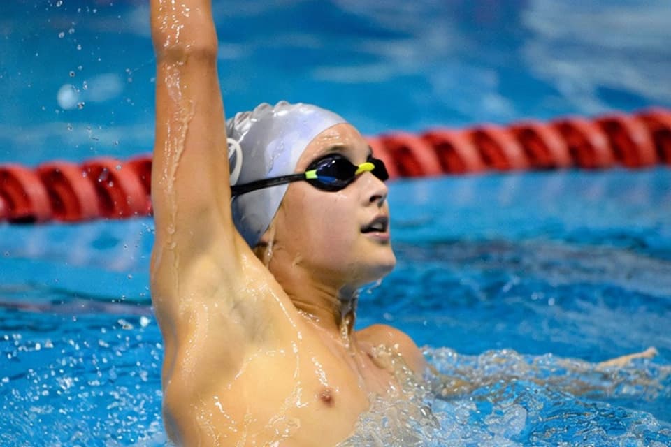 Parents scrolling through swim rankings on their phones while looking worried