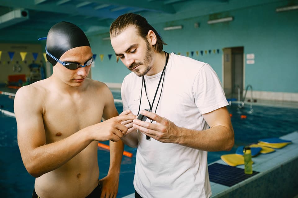 Coach sharing a dashboard with parents and swimmer during a calm conversation